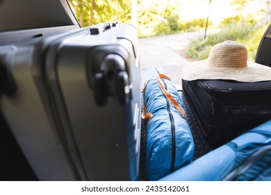 A car trunk is packed with luggage and a straw hat for a trip. the scene suggests preparation for a journey, a vacation or outdoor adventure.: stockfoto