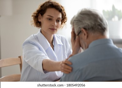 Caring young woman doctor comforting depressed unhealthy mature patient at meeting in hospital, therapist physician gp caregiver touching senior man shoulder, expressing empathy and support स्टॉक फ़ोटो