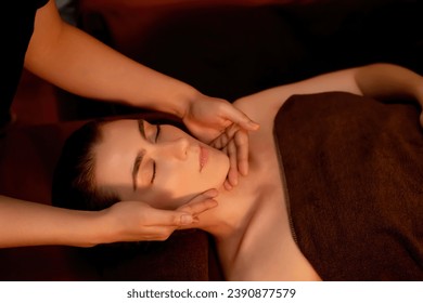 Une femme caucasienne profitant d'un massage relaxant de la tête anti-stress et d'un loisir de beauté faciale dans le spa salon à l'éclairage de bougies dans un complexe de luxe ou un hôtel. Quiescent : photo de stock