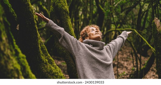 自由と自然の愛を祝う。緑の木の幹とムスクを背景に森の中で腕を伸ばす1人の女性。自然で健康的なライフスタイルで幸せと健康レジャーで人々の写真素材