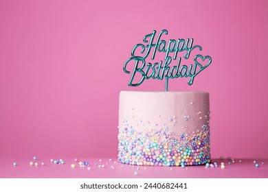 ピンクの背景にお祝いの誕生日ケーキと幸せな誕生日ケーキピックの写真素材