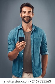 Cellphone, smile and portrait of man in studio, communication and social media on gray background. Internet, online and scroll for texting on dating app, talk or happy male person on mobile for love: stockfoto