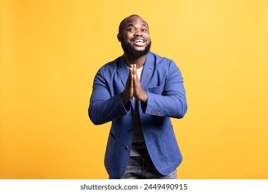 쾌활한 아프리카계 미국인 남자가 감사 표시로 손을 맞잡고 감사하다고 말하고 있습니다. 행복한 BIPOC 남자 칭찬하는 몸짓을 하는, 스튜디오 배경에 고립 스톡 사진