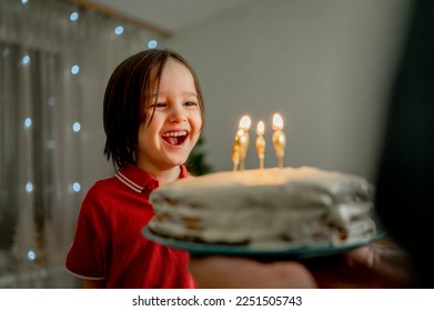 家でバースデーケーキを持つ父と陽気でかわいい男の子の写真素材