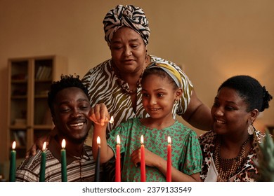 Cheerful family lightning candles in holder prepared for Kwanzaa celebration: stockfoto