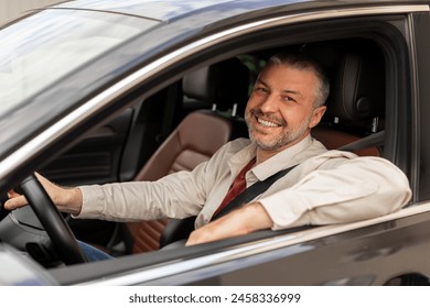 Cheerful middle aged man driving auto, looking through open window and smiling at camera, happy driver enjoying car ride Foto stock