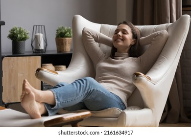 Cheerful relaxed beautiful 20s girl resting in comfortable armchair with closed eyes, peaceful smile, comfort, breathing fresh air. Smiling at good thoughts, laughing. Cozy home, relaxation concept Arkistovalokuva