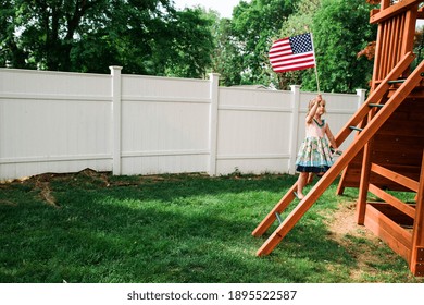 Child climbing up a wooden play structure with an American flag Stock Photo