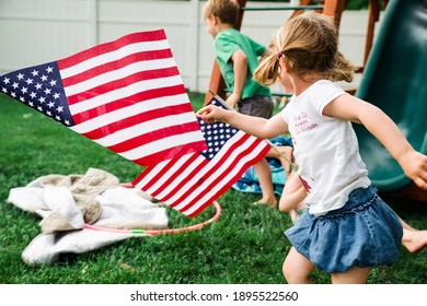 Children running in backyard with American flags Stock Photo