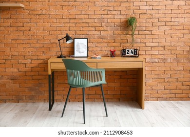 Comfortable workplace near brown brick wall in interior of room Stock-foto