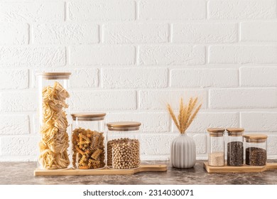 Compact, stylish storage of bulk products in glass jars with bamboo lids. front view. White brick wall. kitchen background, fotografie de stoc