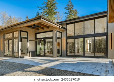 Contemporary modern home exterior with black framed floor to ceiling windows cedar siding painted white brick walls glass and black garage doors elegant slim line exterior light fixtures and flat roof 库存照片