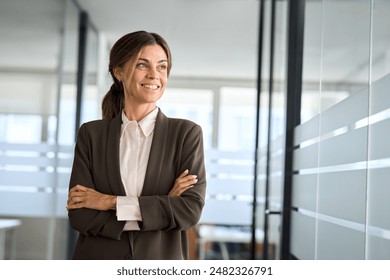Confident 45 years old woman business owner standing in office. Middle aged businesswoman manager, mature female professional executive, corporate leader wearing suit looking away thinking of success. स्टॉक फोटो