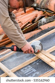 construction worker on a renovation roof covering it with tiles using hammer, crane and grinder Foto stock