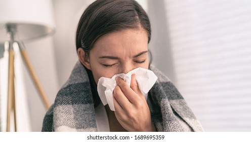 Cough in tissue covering nose and mouth when coughing as COVID-19 hygiene guidelines for coronavirus spread prevention. Asian woman sick with flu at home. स्टॉक फ़ोटो