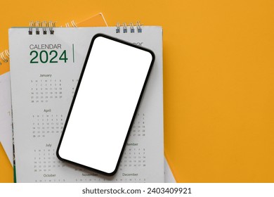 close up top view on  blank screen smartphone with calendar 2024 schedule with on yellow color background to make appointment meeting or manage timetable each day for design plan work and life concept 庫存照片
