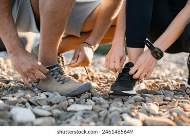 Vista de cerca de las manos de hombre atlético en camiseta blanca y mujer en negro top atando cordones de zapatos antes de hacer ejercicio en la terraza de la azotea. Foto de stock