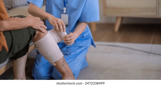 アジアの介護者が自宅で女性の足を包帯する接写。高齢者ケアと創傷管理の概念の写真素材