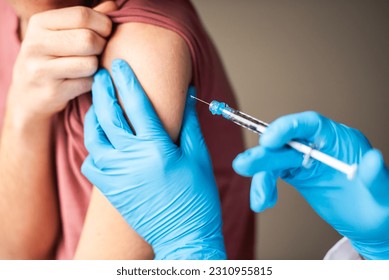 Close up of arm of boy getting vaccinated by doctor holding a needle. Arkistovalokuva