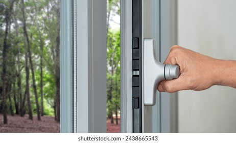 Close up of a male hand closing a double glazed window. Thermal and acoustic insulation. Government grants for energy efficiency at home. Arkistovalokuva