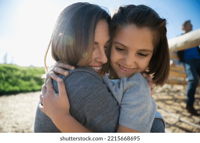Close up mother and daughter hugging sunny playground Stock Photo