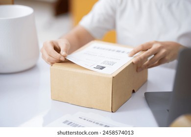 Closeup Male entrepreneur startup small business owner packing package preparing delivery parcel and attaching data label on carboard box on desk. Owener of small business packing product in boxes. 库存照片