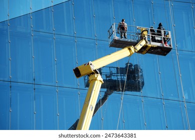 Cleaner worker using a cherry picker to clean a glas facade of a contemporary office building.: stockfoto