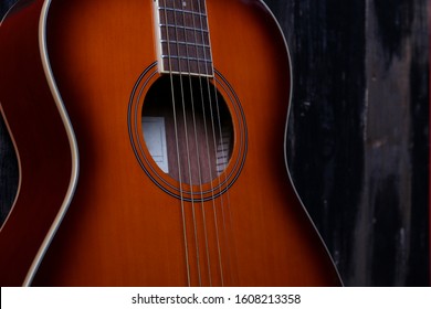 Cropped image of vintage style travel size acoustic guitar with rosewood neck and no pickguard on grunged dark wood textured background. Close up, copy space for text, top view. Arkistovalokuva