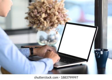 オフィスのデスクで、モックアップノートパソコンを使って若い男性のショットを撮影。の写真素材
