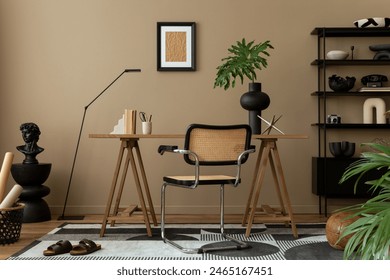 Creative composition of workplace interior with mock up poster frame, wooden desk, rattan chair, black rack, patterned rug, plant, brown wall, books and personal accessories. Home decor. Template. Arkistovalokuva