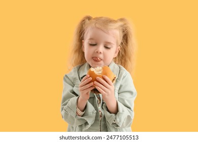 Cute little girl with burger on yellow background – Ảnh có sẵn