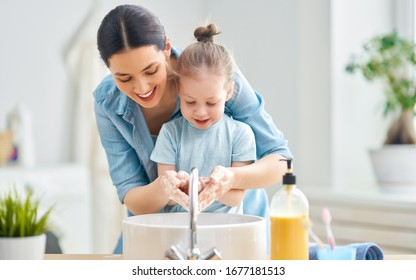 A cute little girl and her mother are washing their hands. Protection against infections and viruses.                                Stock Photo