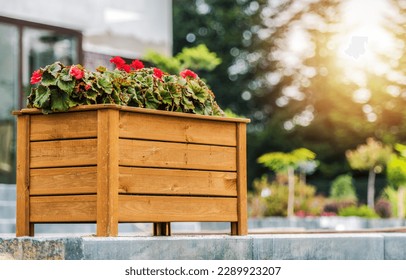 Decorative Wooden Planter Box with Blooming Red Flowers Arranged in the Residential Backyard Garden. Landscaping Design Ideas. Stock-foto