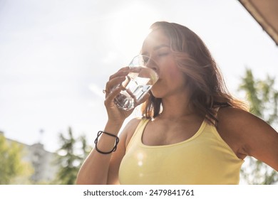 Dehydrated woman drinks clean water from a glass to replenish fluids during hot summer days. 库存照片