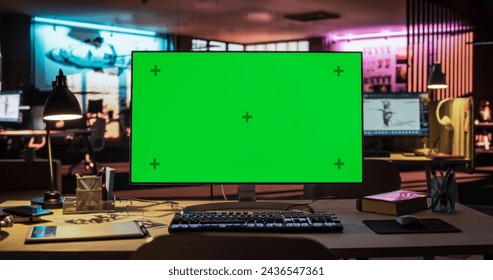Desktop Computer with Mock Up Green Screen Chroma Key Display Standing on the Desk in the Empty Creative Office Lit by Neon Lights. Monitor in Game Development or Animation Company Stockfoto