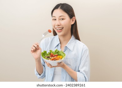 Diet concept, happy smile asian young woman use fork to prick tomato, fresh vegetable or green salad, eat nutrition food isolated on background, low fat to good body, getting weight loss for healthy. Stock-foto