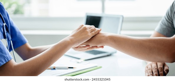 A doctor and patient shake hands in a medical setting. The patient is wearing a gray shirt – Ảnh có sẵn