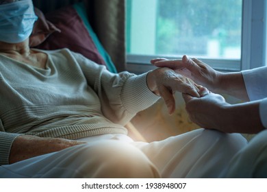 Doctor worriedly and holding the senior woman's hand, elderly wearing medical mask, general practitioner visiting her at home, elderly health care concept, selective focus स्टॉक फ़ोटो