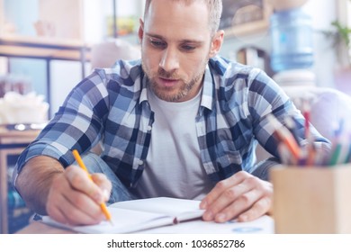 Do this task. Handsome man looking downwards and being serious while making notes Foto stock