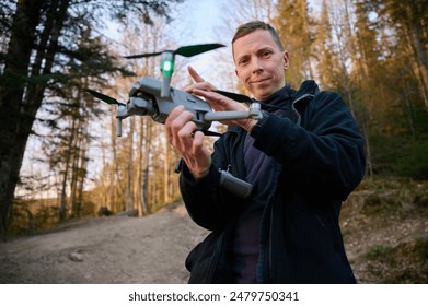 Drone operator holding remote controller and drone in hands. Start flying from the hand. Drone Pilot Releasing Drone camera from its hand. Aerial nature photography and videography. Arkistovalokuva