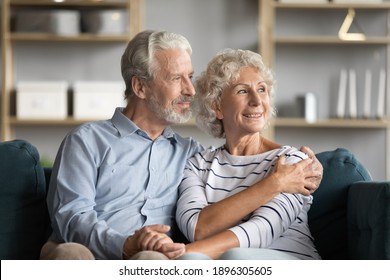 Dreamy middle aged senior loving retired family couple looking in distance, planning common future or recollecting memories, enjoying peaceful moment relaxing together on cozy sofa in living room. – Stockfoto