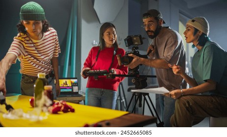 Dynamic Young Film Crew Engaged In A Lively Discussion On A Colorful Set, With A Female Asian Cinematographer Adjusting A Camera As Her Diverse Team Collaborates On A Creative Video Production Project Arkistovalokuva