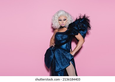 eccentric drag queen in blue dress standing with hand on hip on pink 库存照片