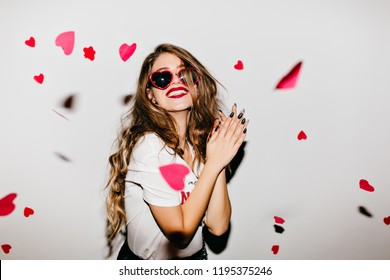 バレンタインデーで前向きな感情を表す長い髪の気楽な女の子。落ちた紙の心を見て笑う興奮した女性。の写真素材