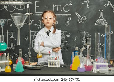 Educación y desarrollo temprano de los niños. Una niña de bata blanca -una joven científica- lleva a cabo experimentos en un laboratorio químico. Foto de stock