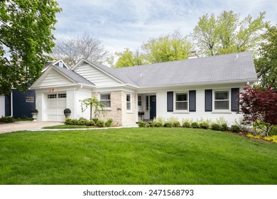 Elmhurst, IL, USA - April 28, 2023: A beautiful suburban home with a white brick and stone siding, beautiful landscaping, and a rose gold light over the garage. Toimituksellinen arkistovalokuva