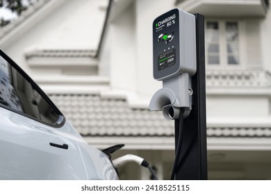 EVカーのバッテリー充電のために住宅地や家庭用充電ステーションに利用される電気自動車技術。クリーンで持続可能なエネルギーによる環境に優しい輸送で、将来の環境に貢献します。同期の写真素材