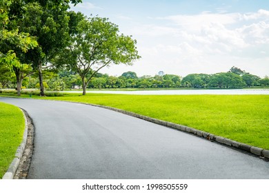 푸른 하늘이 있는 아름다운 녹색 도시 공원.달리기와 산책을 위한 길과 아름다운 나무들의 트랙은 옆에 있는 푸른 잔디밭에 있는 공원에서 휴식을 취한다.햇빛과 플레어 배경 개념 스톡 사진