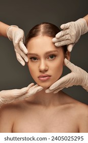 estheticians in medical gloves examining face of young woman on grey background, dermatology concept Stockfotó