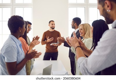 Excited businesspeople applaud successful male speaker or trainer for presentation or lesson at meeting. Happy employees clap hands show appreciation acknowledgement to team leader for speech. Arkistovalokuva